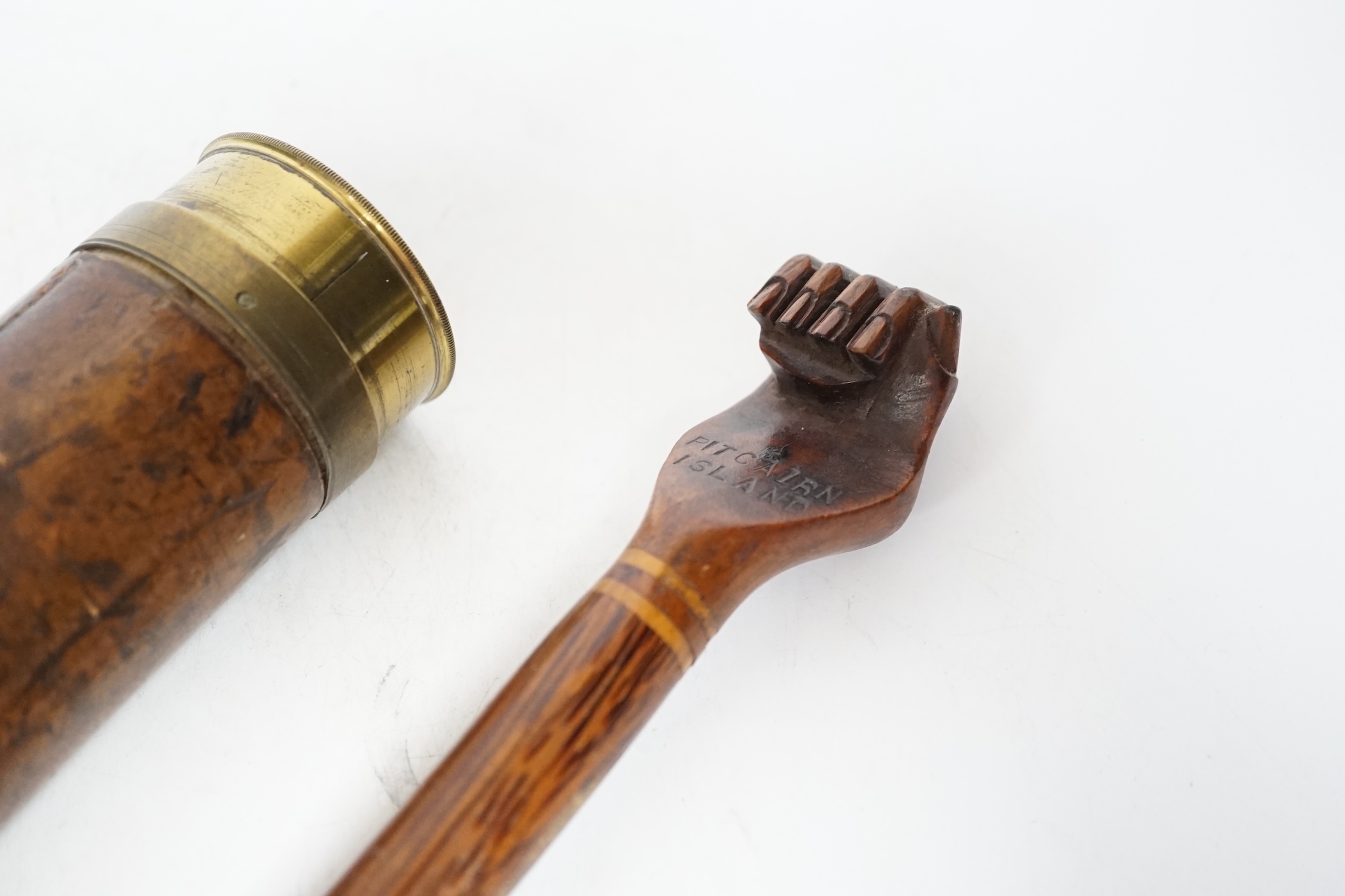 An inscribed cocus wood walking stick with carved handle in the form of a hand, ‘Pitcairn Island’ and a brass mounted two drawer telescope, largest 92cm in length